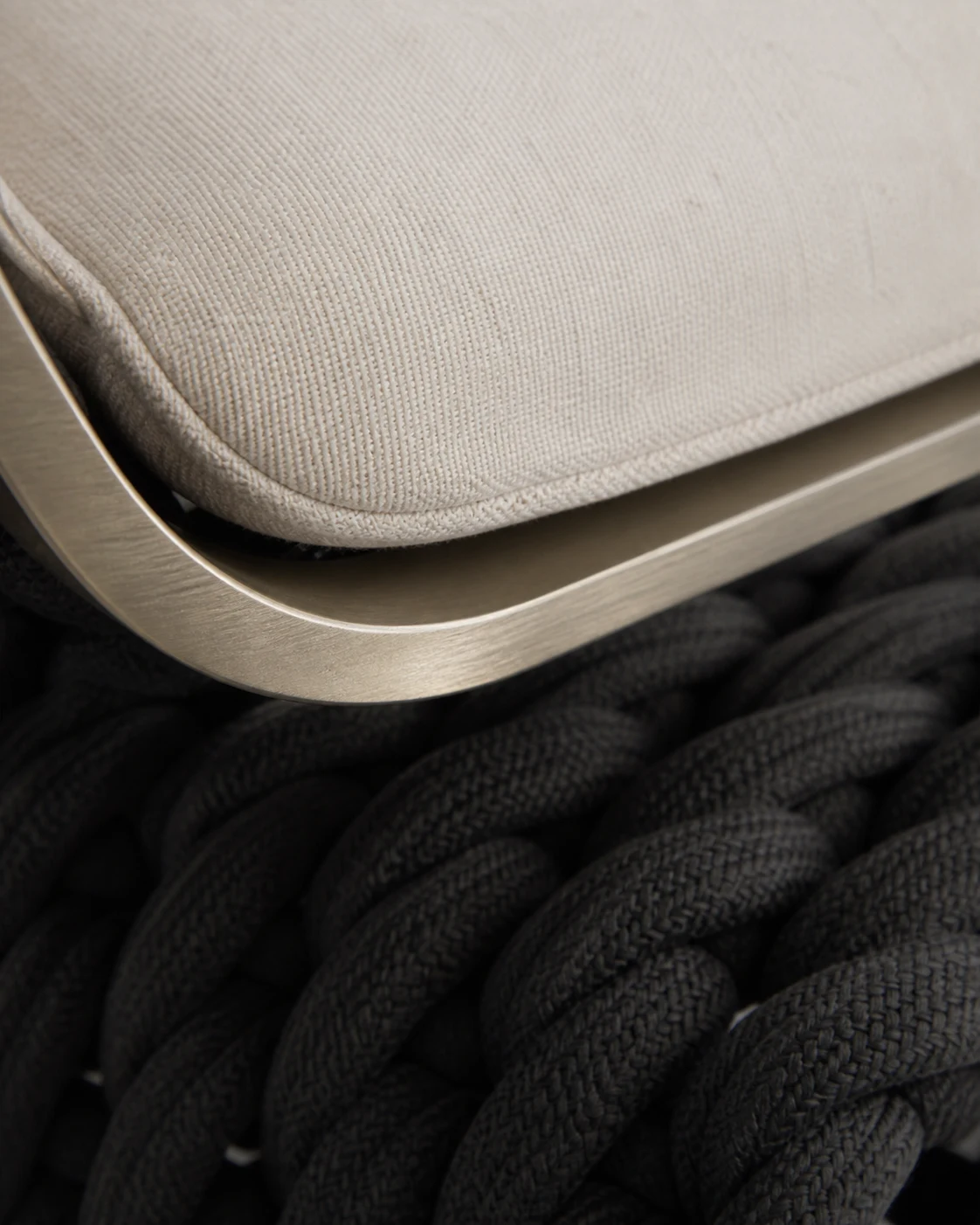 Close detail of cream upholstery meeting the metal frame and dark weave