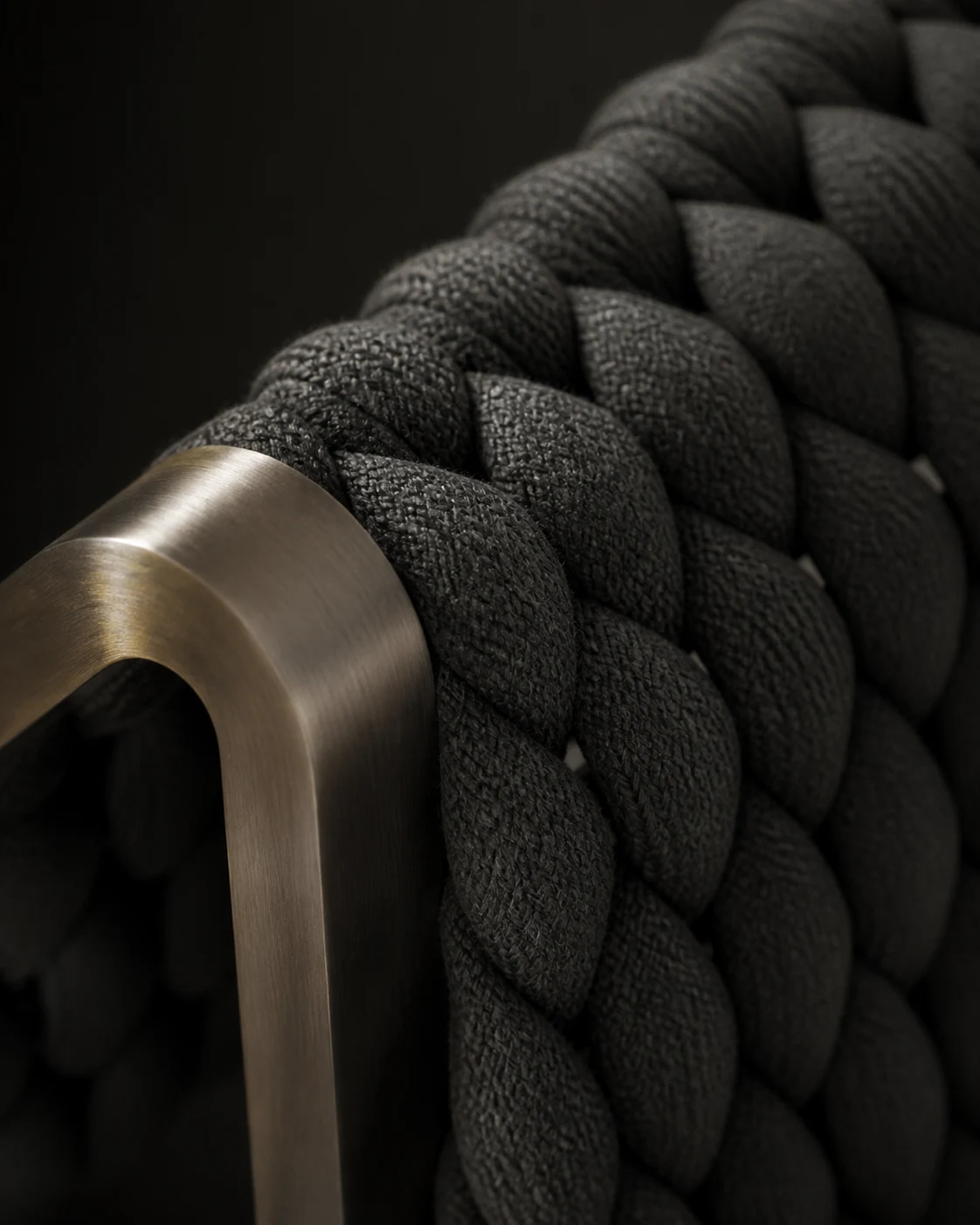 Close detail of the sofa's charcoal woven side and metal frame